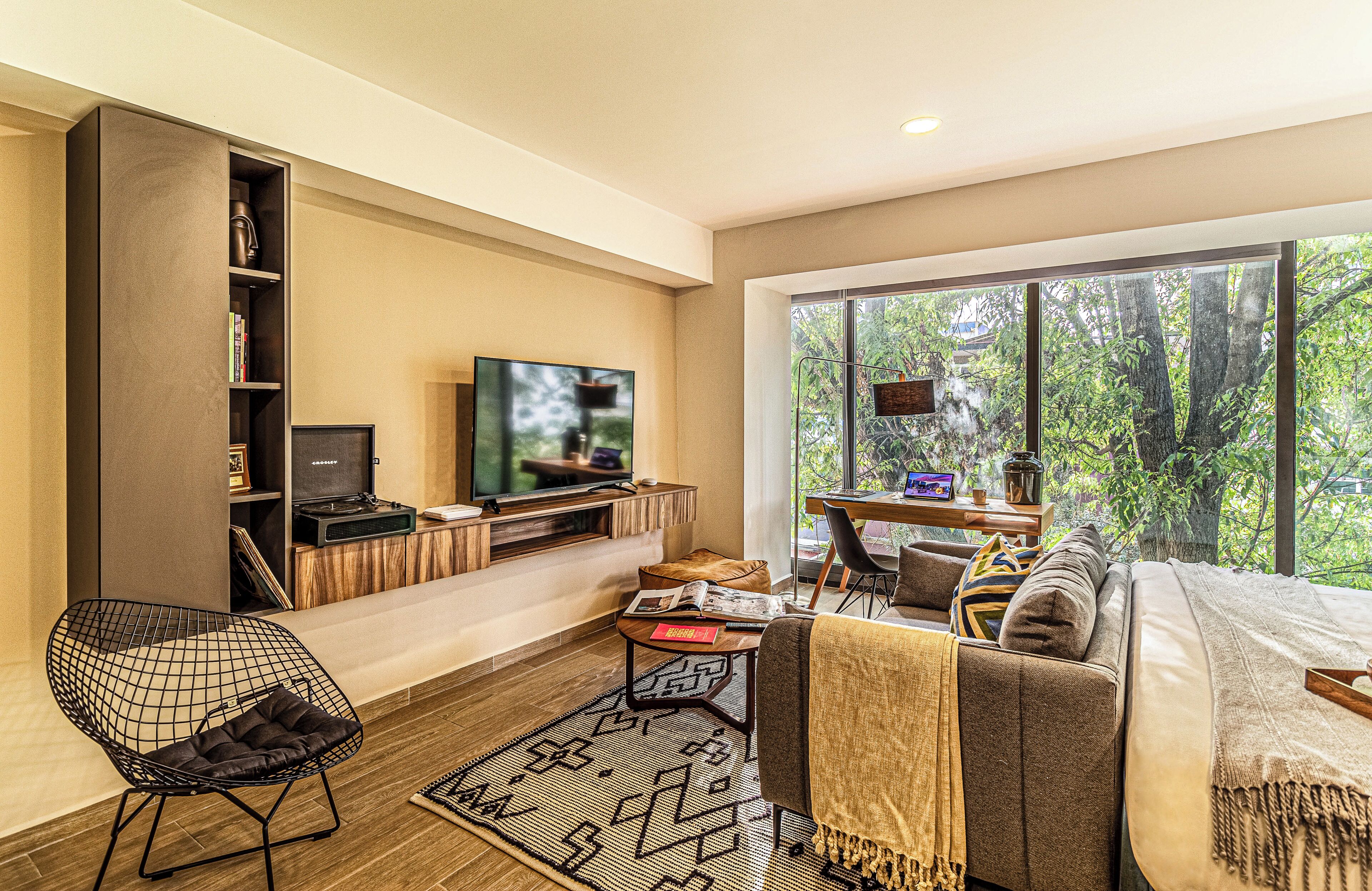 A modern living room with a TV, seating, and a large window.