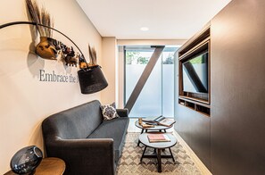 Un interior moderno con un sofá gris, una mesa de centro y una estantería de pared con objetos decorativos.