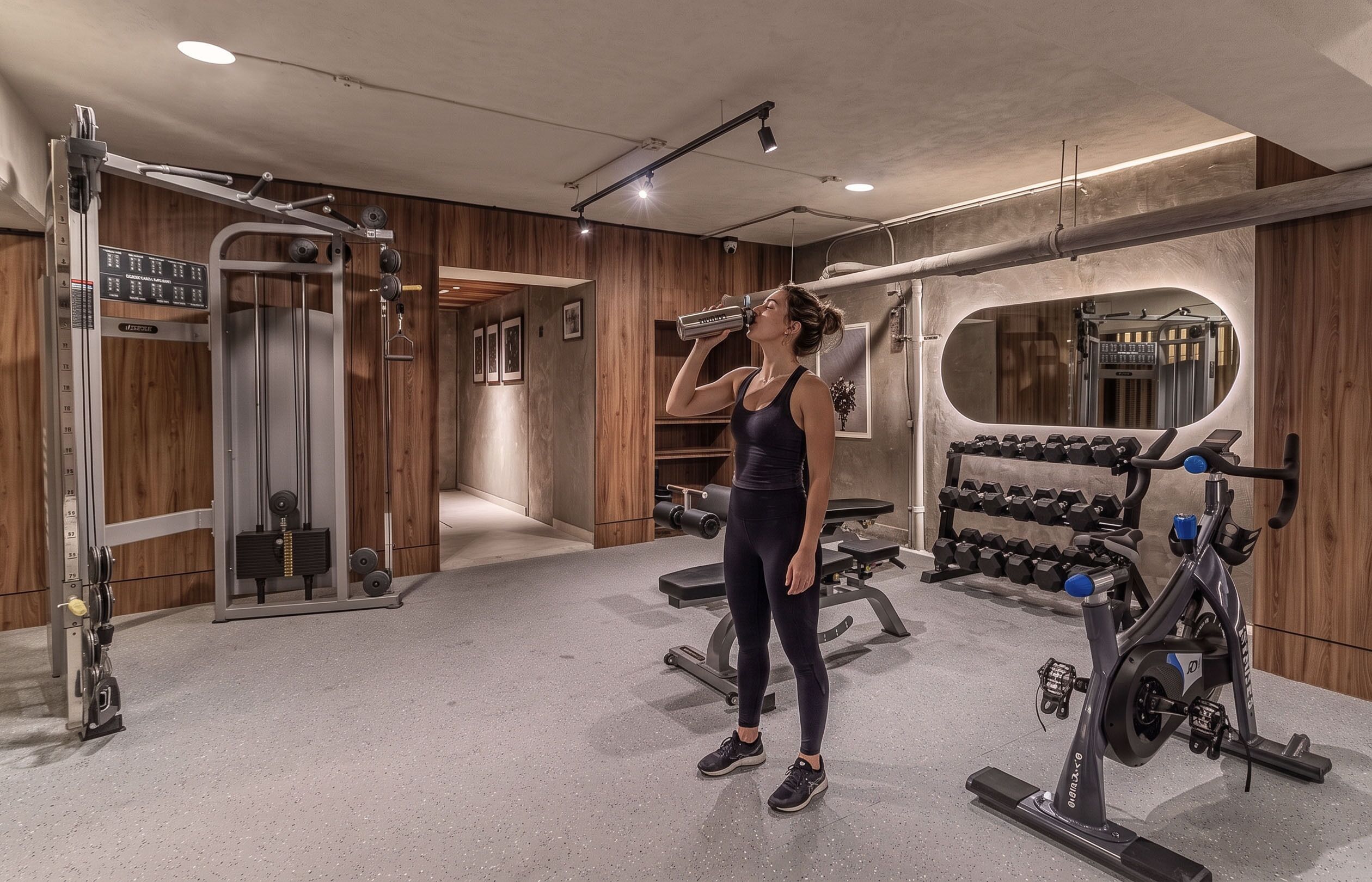 Un gimnasio con equipo de levantamiento de pesas, un espejo y paneles de madera.