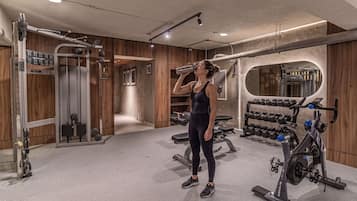 Un gimnasio con equipo de levantamiento de pesas, un espejo y paneles de madera.