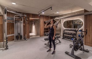 A gym with weightlifting equipment, a mirror, and wooden paneling. - Kukun Tonalá 30 Roma (Mexico City)