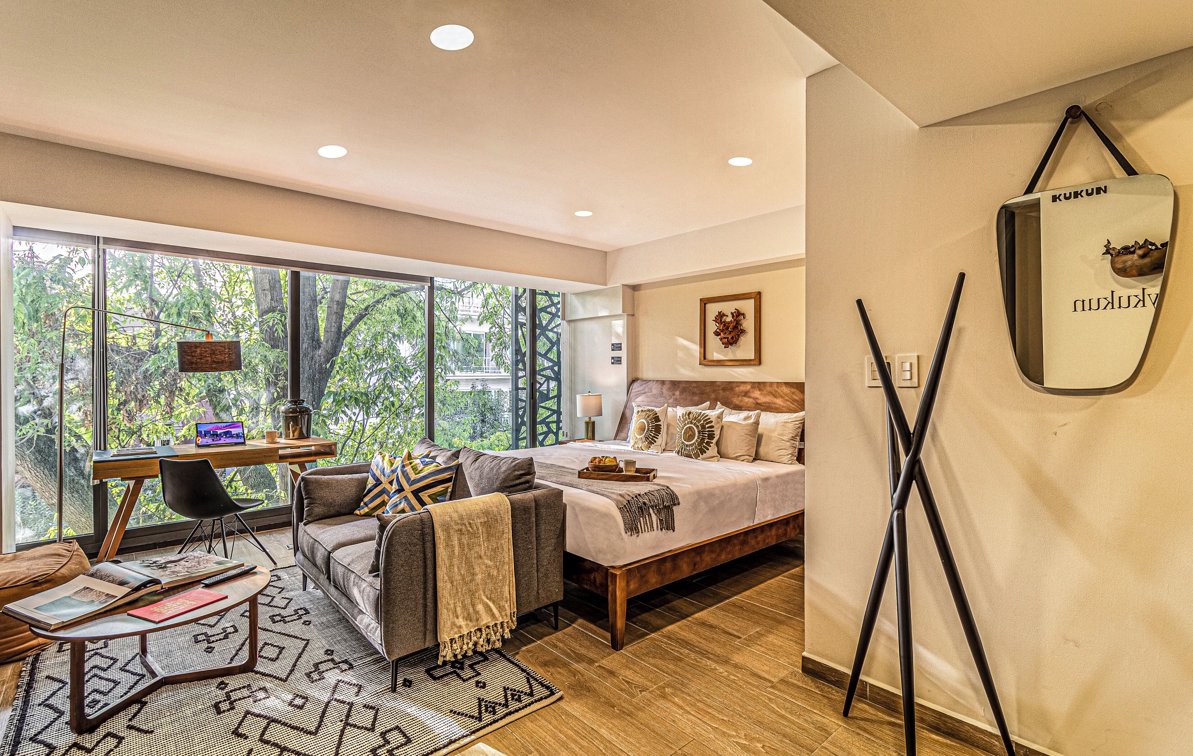A modern bedroom with a large window, a bed, a desk, and a chair.