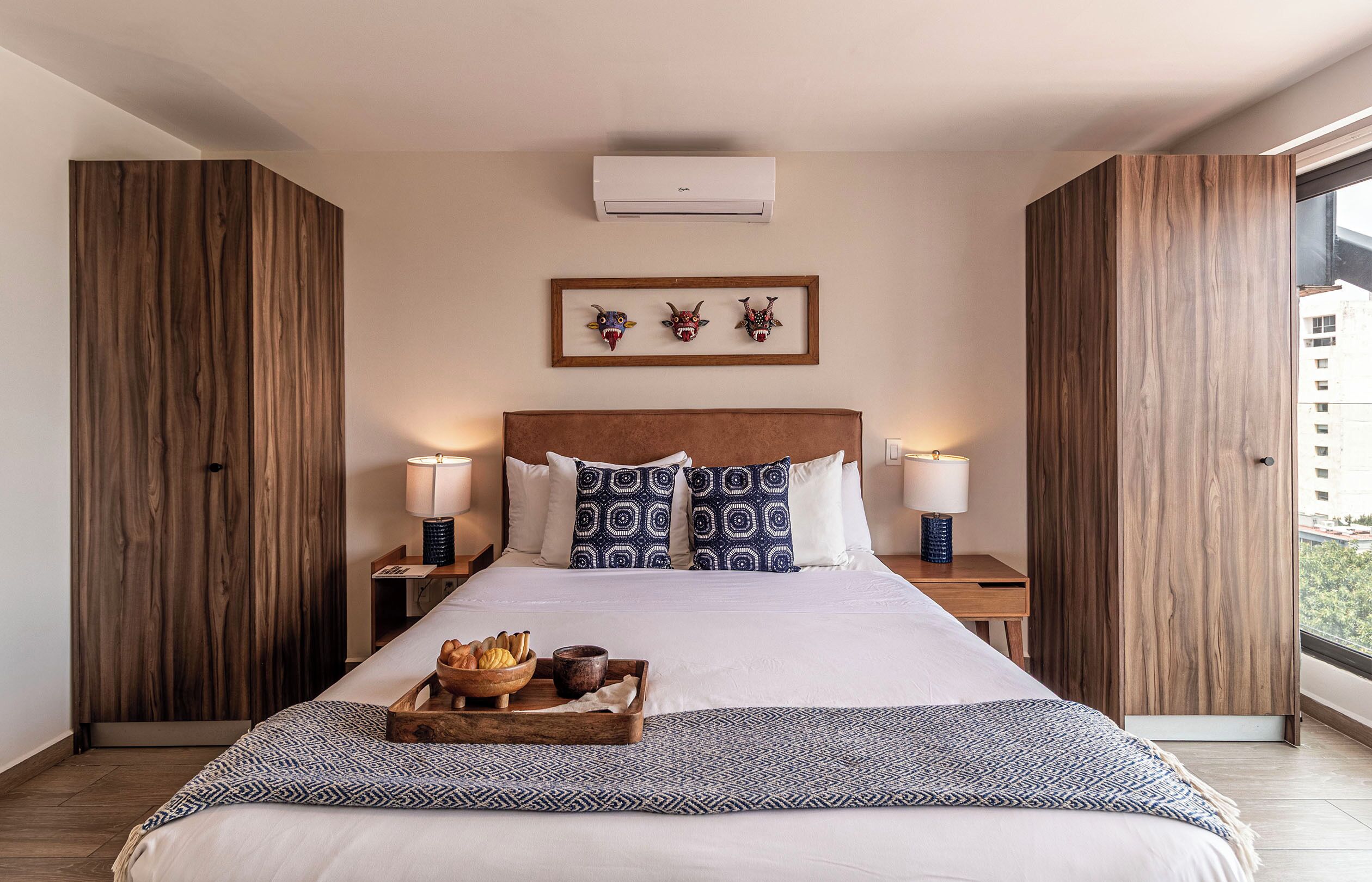 Une chambre d’hôtel moderne avec un grand lit, des panneaux de bois, une œuvre d’art encadrée et une vue sur la ville.