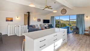 A spacious living area with a large island, a ceiling fan, and a view of the outdoors.