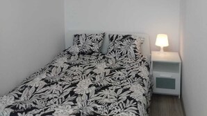 Et soveværelse med seng, natbord, lampe og pendel.