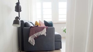 Un salon moderne avec un canapé gris, une lampe sur pied et une fenêtre ornée de rideaux blancs.