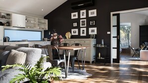 A modern living room with a dining area, a kitchen, and a view of the outdoors.