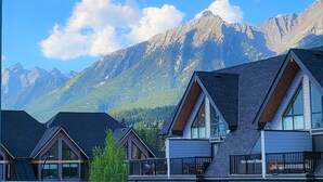Una hilera de cabañas modernas con amplias ventanas, con montañas y un cielo despejado de fondo.