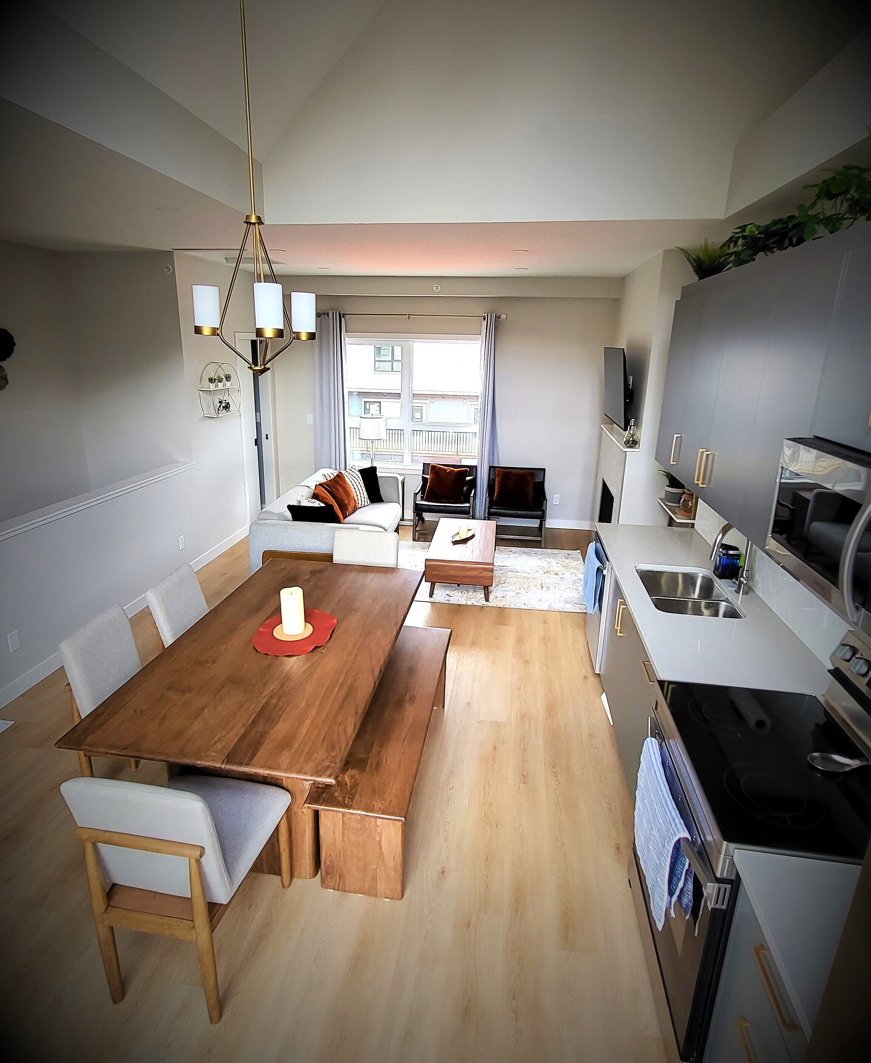 Une cuisine moderne avec un coin repas, une table en bois, des chaises et un four encastré.