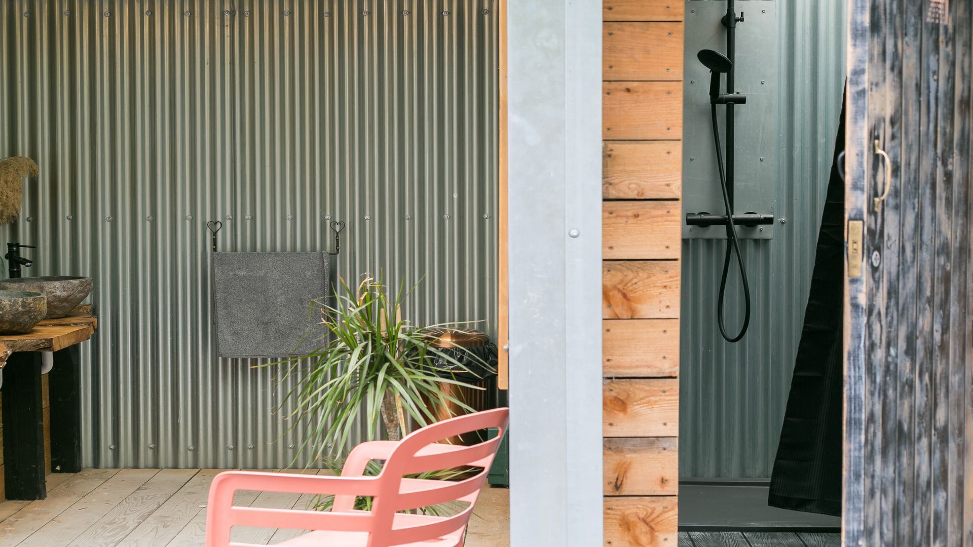 A bathroom with a shower, a towel hanging on the wall, and a potted plant.