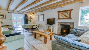 Una sala de estar acogedora con chimenea, vigas de madera, televisor y asientos cómodos.