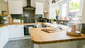 Una cocina moderna con armarios blancos, un salpicadero de azulejos negros y una encimera de madera.