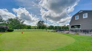 Een golfbaan met een clubhuis, een omheind gebied en een heldere lucht.