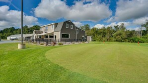 Een groot huis met een verzorgd gazon en een golfbaan op de achtergrond.