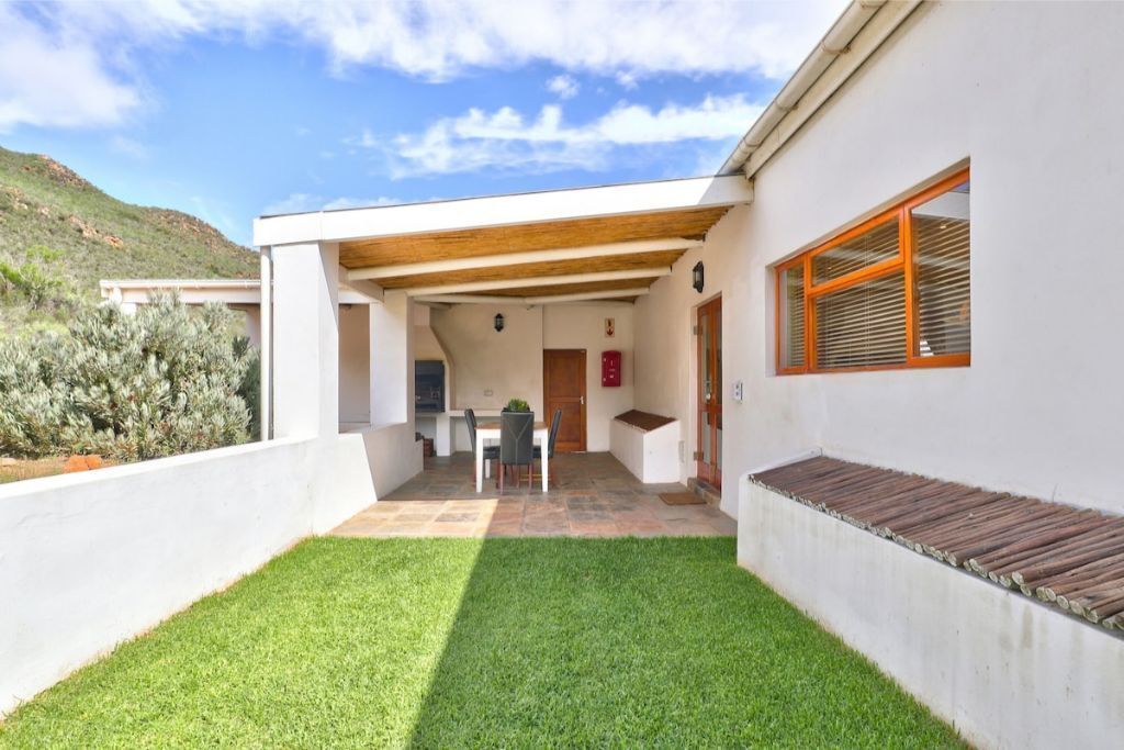 A modern house with a patio, a dining area, and a small garden.