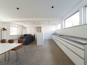 Een moderne keuken met witte kastjes, een koelkast en een eethoek met een tafel en stoelen.