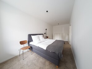 Een slaapkamer met een bed, een stoel en een lamp.