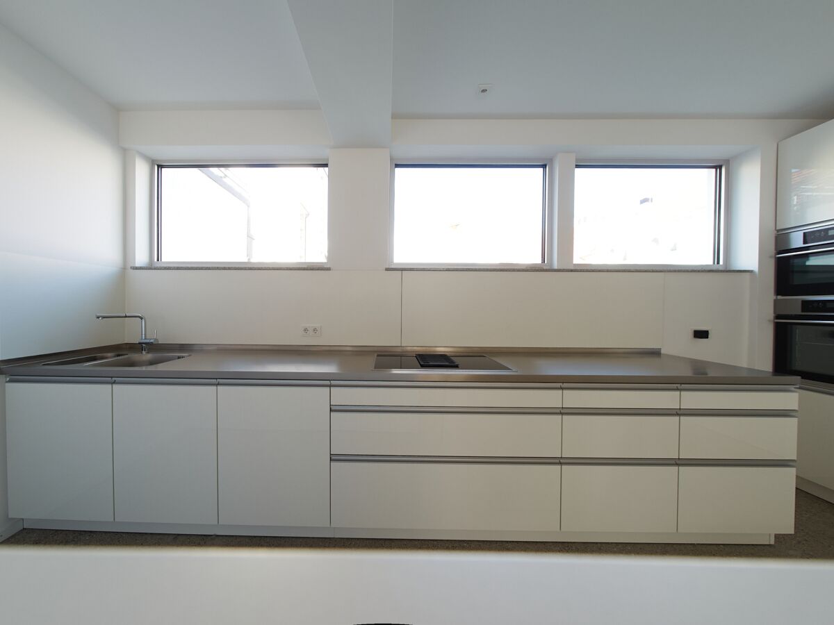 A modern kitchen with a large island, built-in appliances, and large windows.