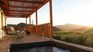 Eine Holzterrasse mit Whirlpool, Stühlen und Bergblick.