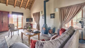 Ein gemütliches Wohnzimmer mit Kamin, bequemen Sitzgelegenheiten und einem großen Fenster.