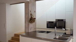 Une cuisine moderne dotée d’un îlot central, d’appareils électroménagers en acier inoxydable et d’un design minimaliste.