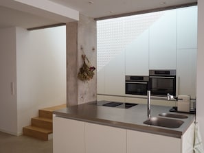 Een moderne keuken met een centraal eiland, roestvrijstalen apparatuur en een minimalistisch ontwerp.