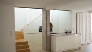 Une cuisine moderne dotée d’un îlot central, d’un four encastré et d’un escalier menant à un niveau supérieur.