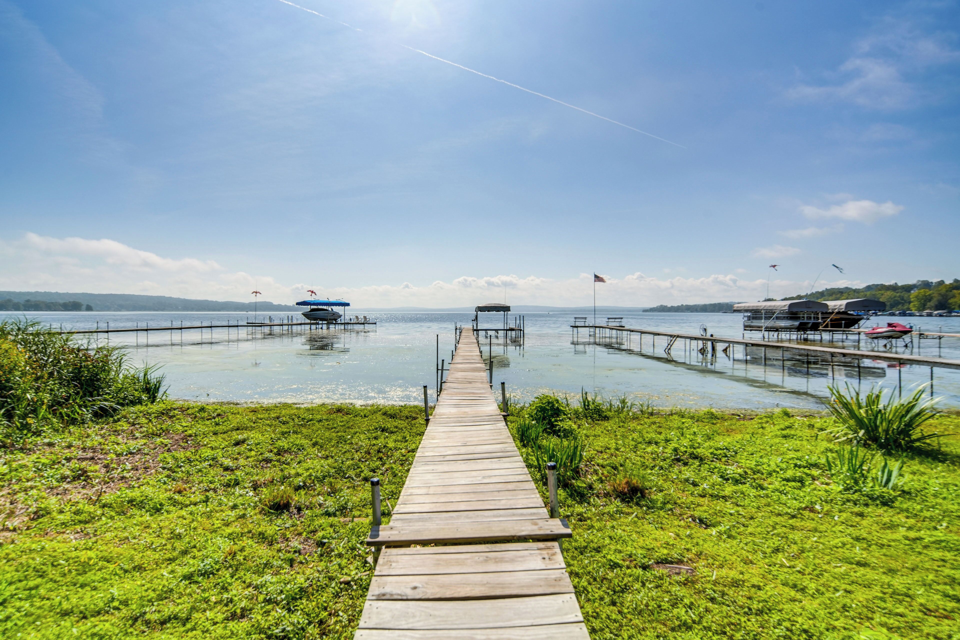 A wooden pier leading to a dock with boats and a clear sky.