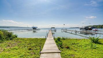A wooden pier leading to a dock with boats and a clear sky.