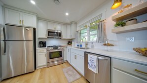 Una cocina moderna con armarios blancos, electrodomésticos de acero inoxidable y piso de madera.