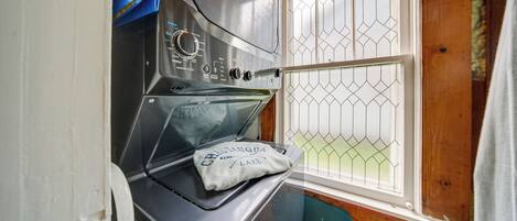 Cocina pequeña con horno empotrado, ventana con reja de metal y una toalla sobre la puerta del horno.