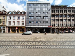 Een straatbeeld met een modern gebouw, met winkels op de begane grond en woningen erboven.