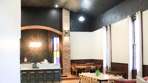 A modern living room with a white sofa, wooden dining table, and a kitchen area with a bar counter.