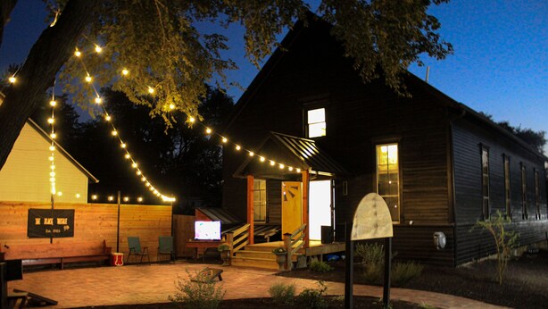 A rustic cabin with a porch, string lights, and a mailbox.