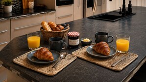 A modern kitchen with a breakfast setup including croissants, juice, and a jar of jam. - ✨ Loft Evasion – Spacious, Stylish & Family-Friendly near Montpellier & Sea  ✨ (Lattes)