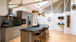 A modern kitchen with a central island, wooden flooring, and pendant lighting. - ✨ Loft Evasion – Spacious, Stylish & Family-Friendly near Montpellier & Sea  ✨ (Lattes)