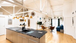 A modern kitchen with a central island, pendant lights, and a high ceiling with skylights. - ✨ Loft Evasion – Spacious, Stylish & Family-Friendly near Montpellier & Sea  ✨ (Lattes)