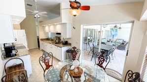 A spacious kitchen with white cabinets, a granite countertop, and a dining area with a glass table and metal chairs. - Minutes From Beautiful White-Sand Beaches (Rotonda West)