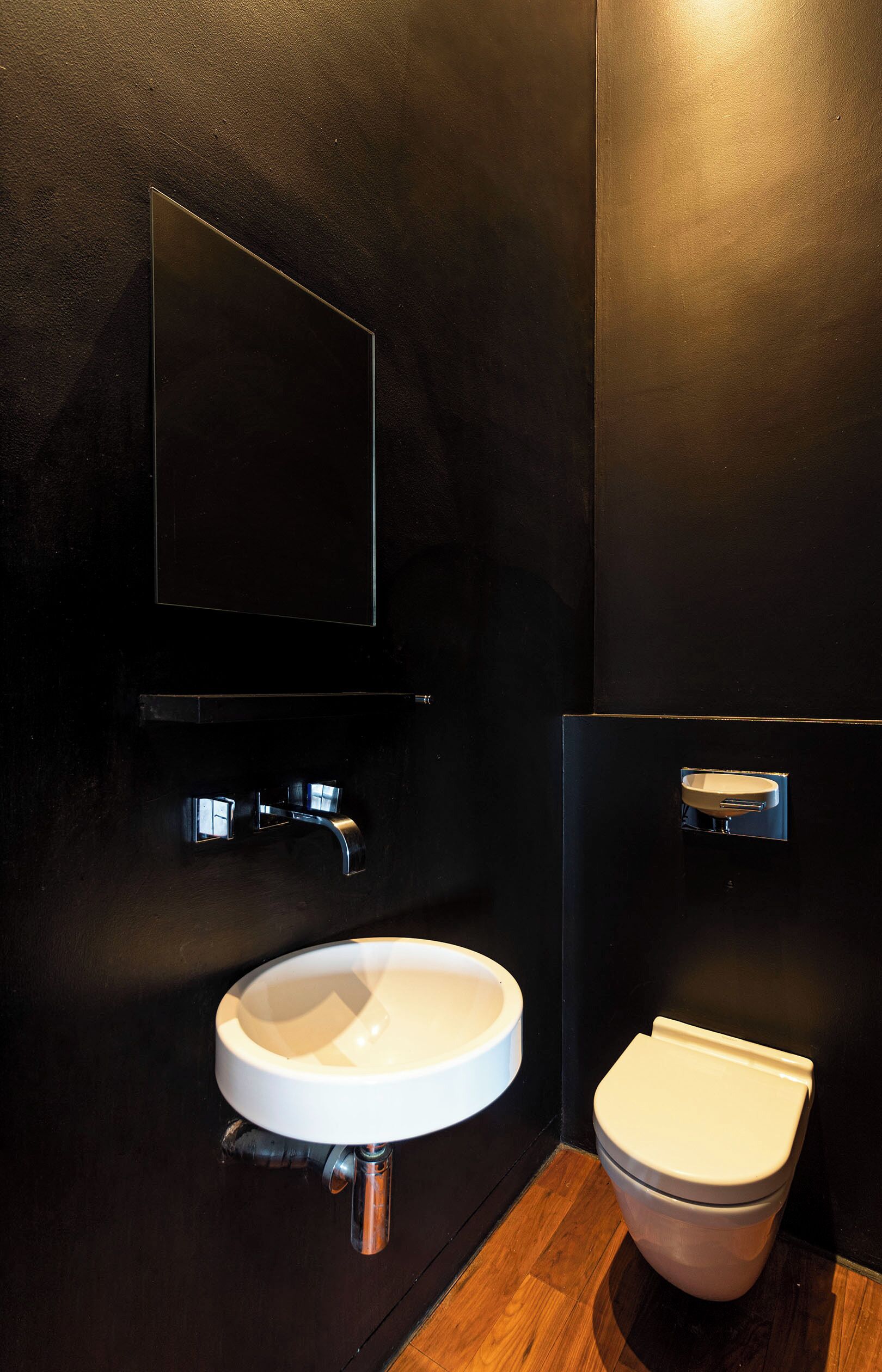 Een moderne badkamer met een witte wastafel, een spiegel en een toilet.