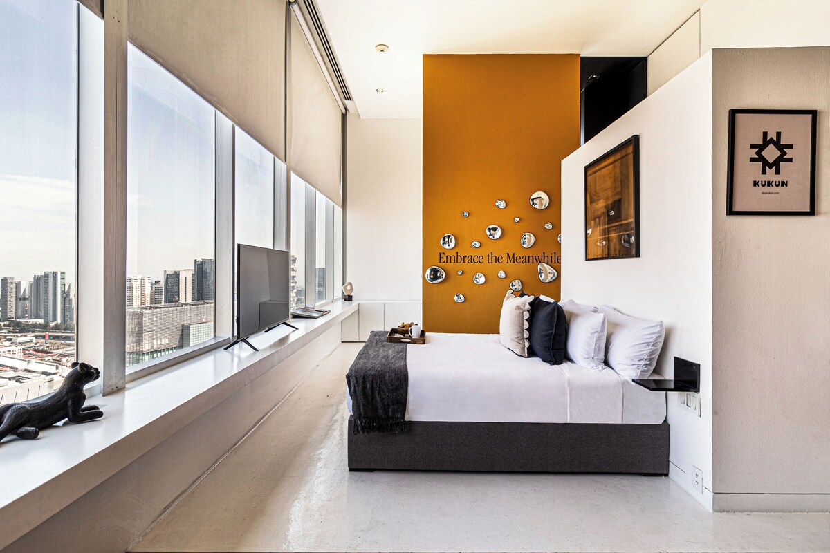 A modern bedroom with a large window, a bed, and a city view.