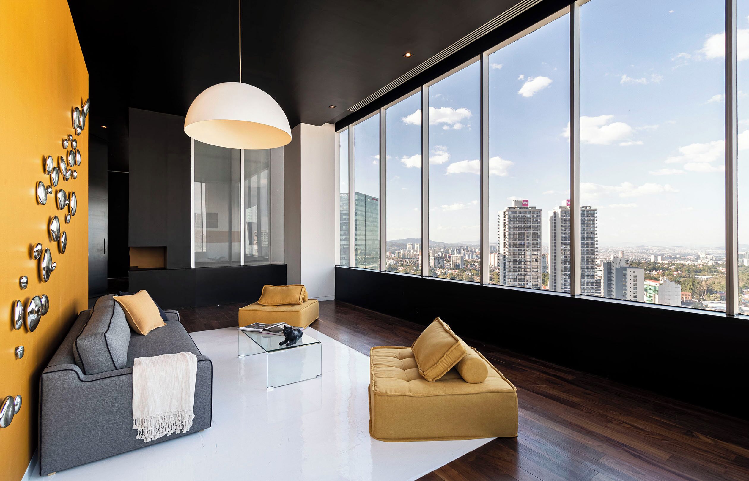 Una sala de estar moderna con un ventanal grande, un sofá, una mesa de centro y detalles decorativos en la pared.