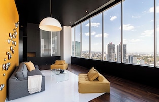 A modern living room with a large window, a sofa, a coffee table, and decorative wall elements.