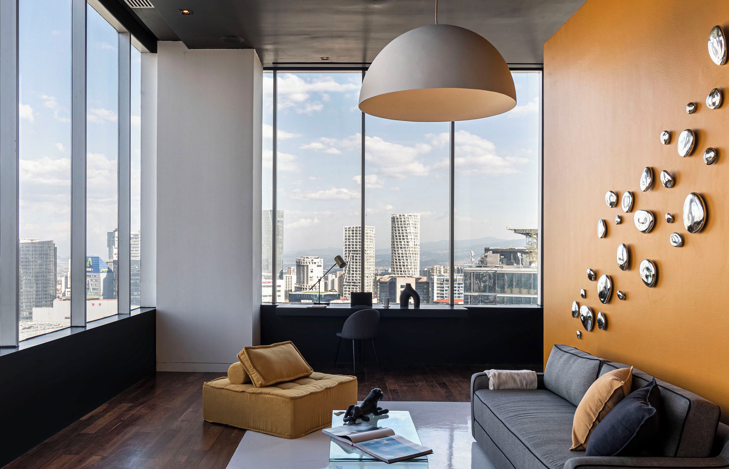 A modern living room with a large window, a sofa, a chair, and a decorative wall.