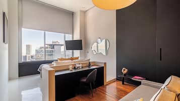 Un dormitorio moderno con un ventanal grande, un escritorio, una silla y una cama.