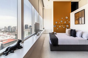 A modern hotel room with a large window, a city view, a bed, a mounted TV, and a decorative wall with a phrase. - Kukun Escape Santa Fe (Mexico City)