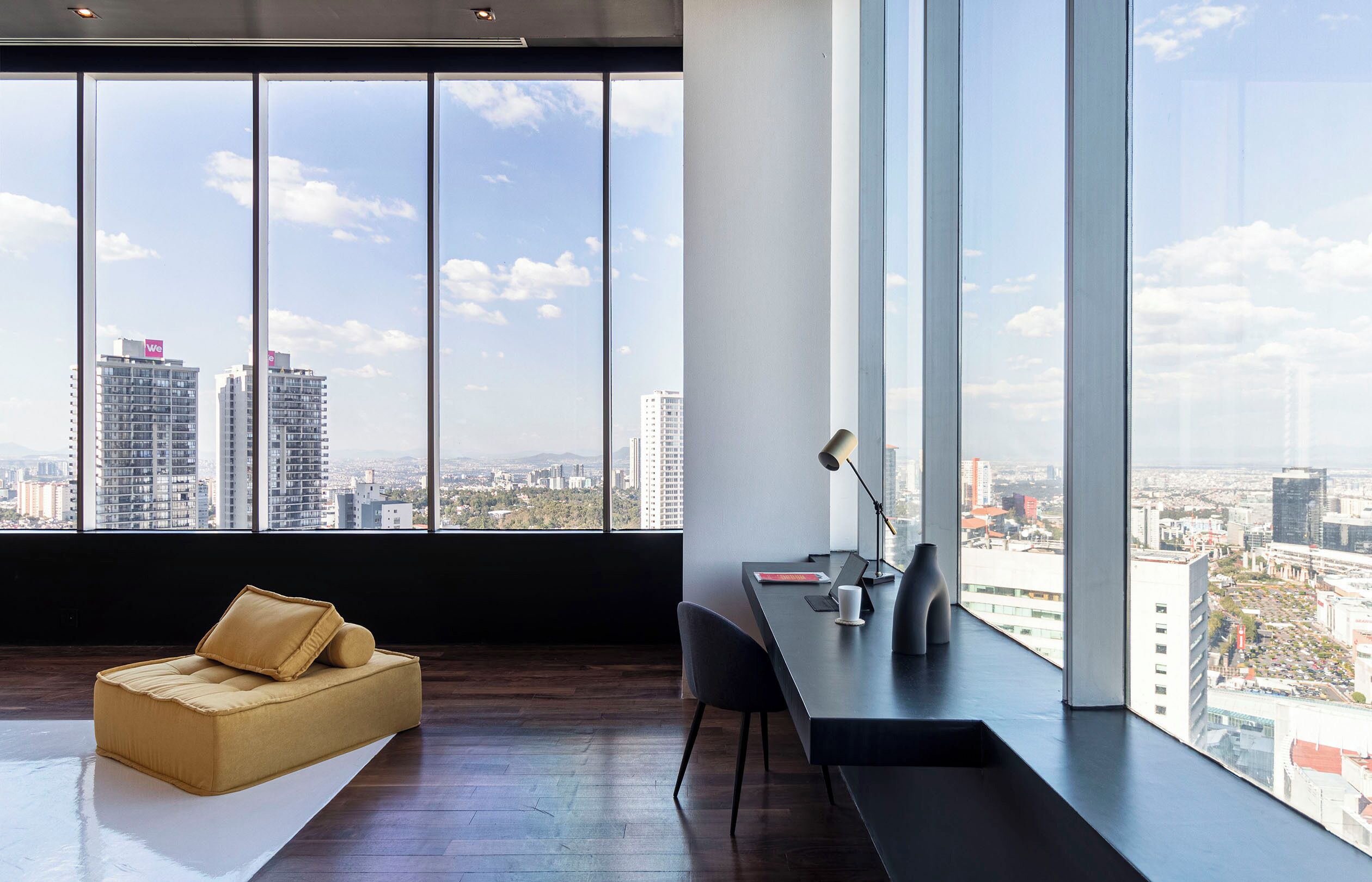 Una habitación moderna con un ventanal grande, un sofá, un escritorio y una silla.