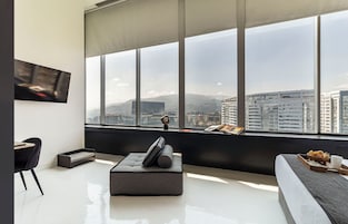 Una sala de estar moderna con un ventanal grande, un televisor de pantalla plana, un sofá, una mesita de centro y un sillón.