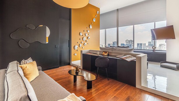 Una sala de estar moderna con sofá, una mesa de centro y vistas a la ciudad a través de amplias ventanas.