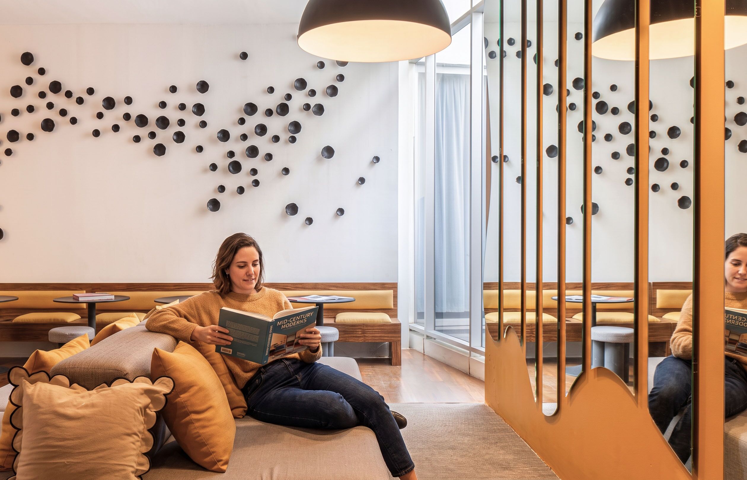 Un interior moderno con una zona de estar, una pared decorada con esferas y un ventanal grande.