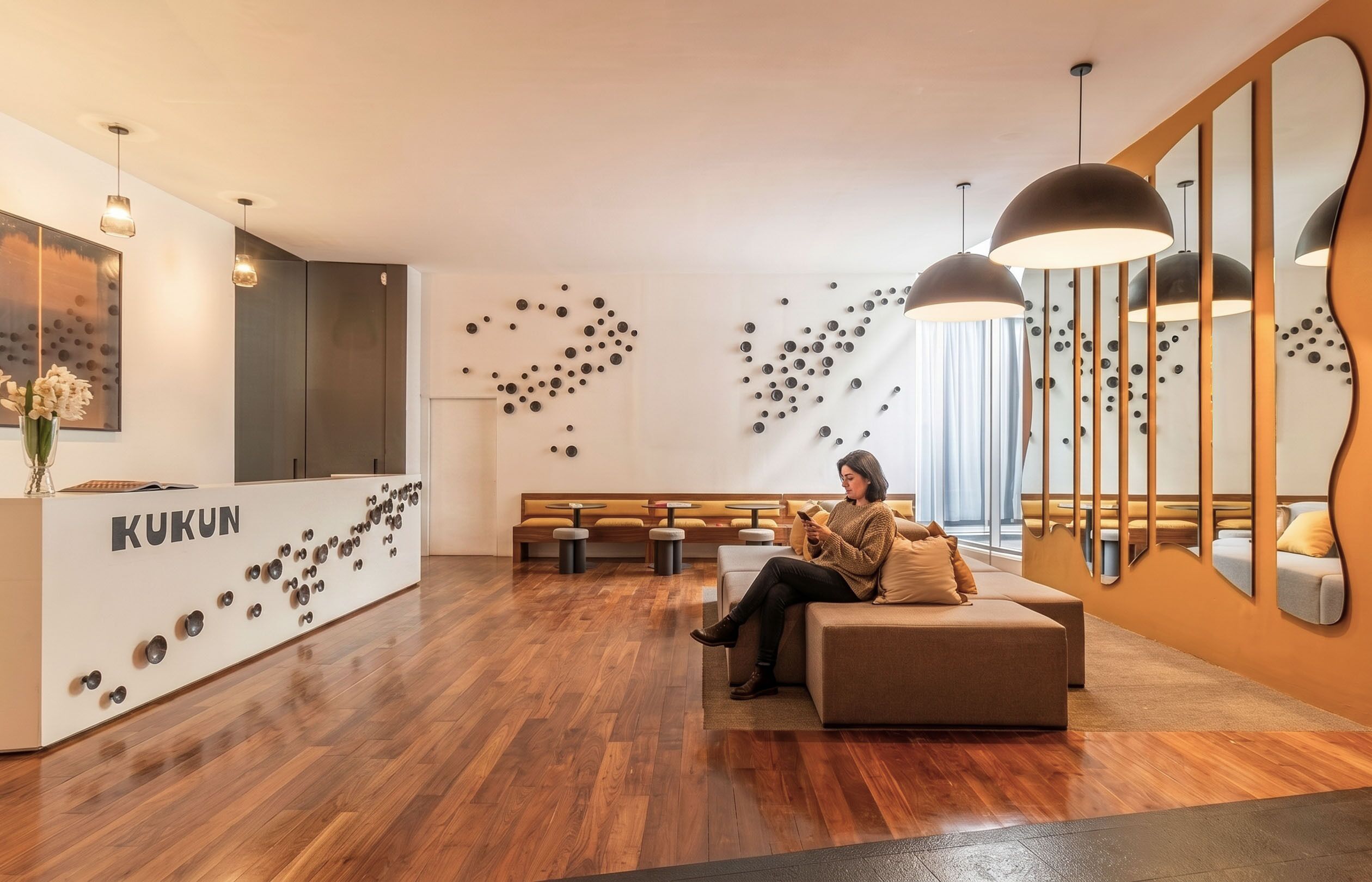 Un espace d’accueil moderne avec un plancher en bois, un coin salon et un réceptionniste.